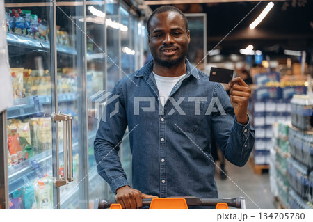 Using and holding credit card. Man customer is in the supermarket Using and holding credit card. Man customer is in the supermarket 134705780