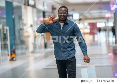 Walking and holding shopping bags. Black man is in the hall of the supermarket 134705816