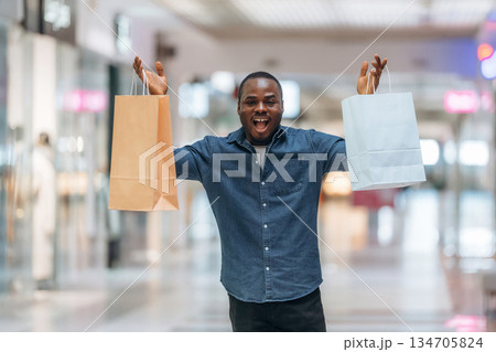 Cheerful facial expression. Black man is in the hall of the supermarket Cheerful facial expression. Black man is in the hall of the supermarket 134705824