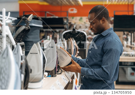 Clothes iron in hands. Man in a home appliance store 134705950
