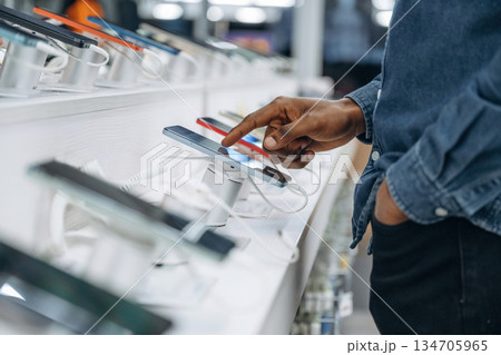 Close up view of man's hand that is touching and trying new smartphone in the store 134705965