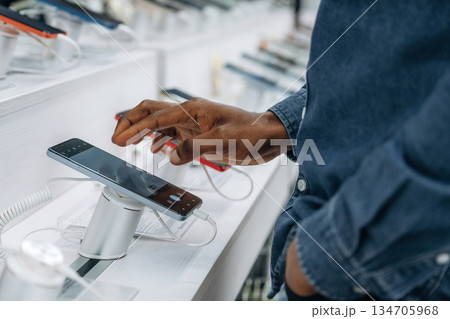 Close up view of man's hand that is touching and trying new smartphone in the store Close up view of man's hand that is touching and trying new smartphone in the store 134705968