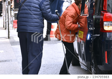 日本の東京都市景観年の瀬。高齢化社会。タクシーが拾えず携帯電話で呼んだ高齢女性。杖の男性は歩くのが… 134705983