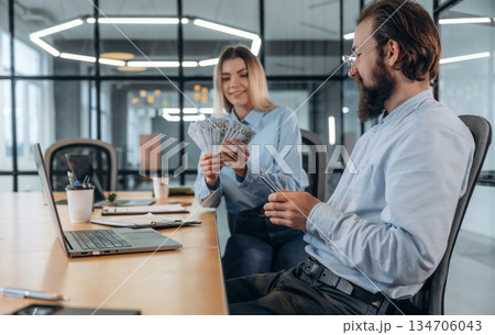 Counting money. Man and woman are in the office together Counting money. Man and woman are in the office together 134706043