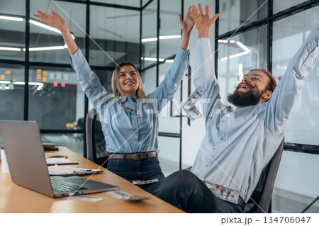Throwing lot of money up in the air. Man and woman are in the office together Throwing lot of money up in the air. Man and woman are in the office together 134706047