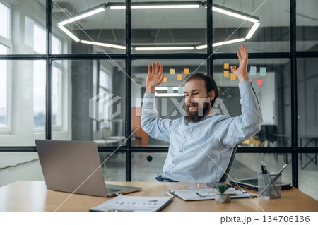 Celebrating success, hands up. Businessman is working in the office 134706136