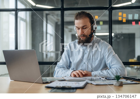 Sitting in headphones, online conference. Businessman is working in the office 134706147