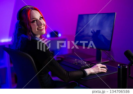 Young female gamer enjoying video games in a neon-lit streaming setup 134706586