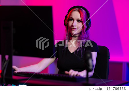 Young female gamer streaming online in a vibrant gaming setup Young female gamer streaming online in a vibrant gaming setup 134706588