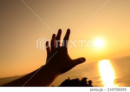 夕日を掴む手のシルエット 夕日を掴む手のシルエット 134706895