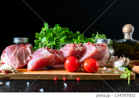Raw Meat with Tomatoes Garlic and Parsley on Cutting Board Raw Meat with Tomatoes Garlic and Parsley on Cutting Board 134707932