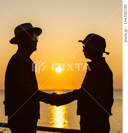 夕焼けの海で握手する二人 夕焼けの海で握手する二人 134708180