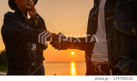 夕焼けの海で握手 134708182