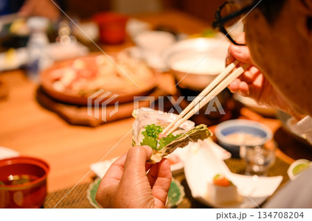 シニアが牡蠣を箸で食べる 134708204