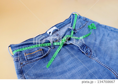 Blue jeans with measuring tape on color background. 134708667
