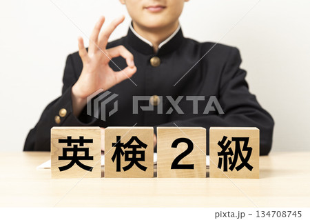 「英検2級」と書かれたブロックとOKサインをする男子学生 134708745