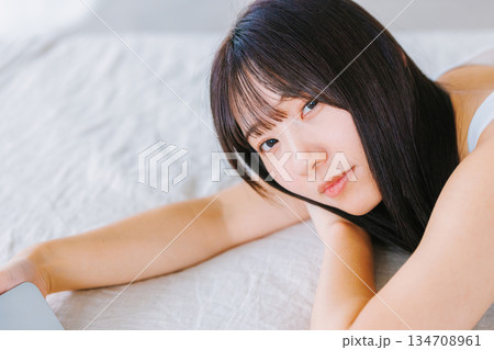 ベットで寝転がってスマホを見る若い女性 ベットで寝転がってスマホを見る若い女性 134708961