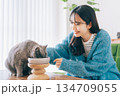 ご飯を食べる猫を見守る女性 134709055
