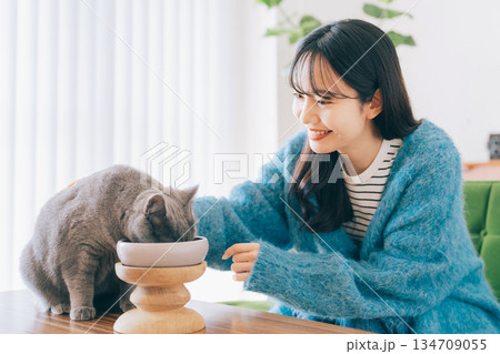 ご飯を食べる猫を見守る女性 ご飯を食べる猫を見守る女性 134709055