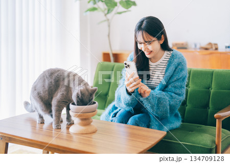 ごはんを食べるネコの写真を撮る女性　 134709128