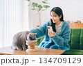 ごはんを食べるネコの写真を撮る女性　 134709129