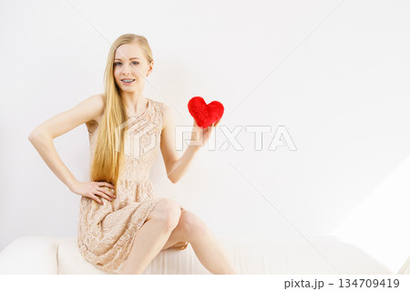 Happy young woman holding red heart Happy young woman holding red heart 134709419