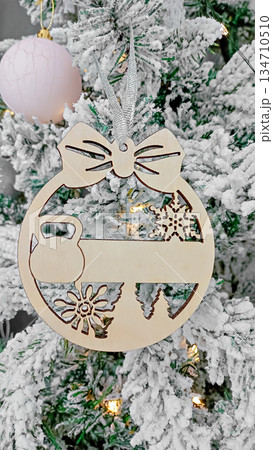 Wooden Christmas ornament with cutout tree shape hanging on rope. Perfect for Christmas, New Year, holiday decoration and festive concepts. Wooden Christmas ornament with cutout tree shape hanging on rope. Perfect for Christmas, New Year, holiday decoration and festive concepts. 134710510