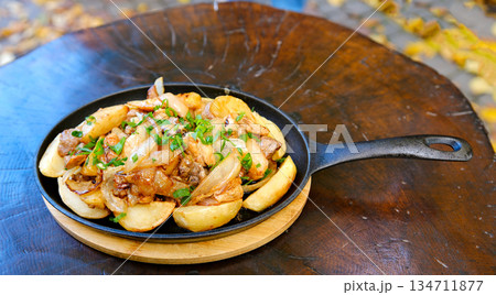 Baked potato with mushrooms and herbs in iron cast pan on wooden table Baked potato with mushrooms and herbs in iron cast pan on wooden table 134711877