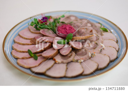 This dish features thinly sliced roast meat arranged elegantly on a platter, complemented by crispy vegetable bites, offering a delightful contrast in texture and flavor. 134711880