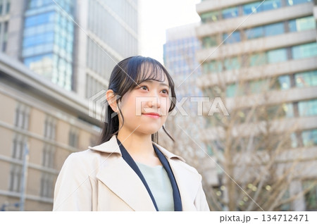 スーツを着てビル街で微笑む20代フレッシャーズのビジネスウーマン 134712471