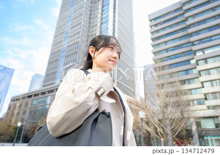 スーツを着てビル街で微笑む20代フレッシャーズのビジネスウーマン 134712479