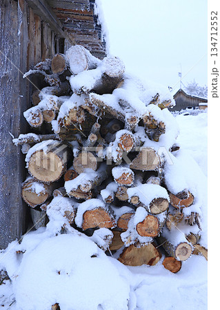 Firewood logs outside under the snow. Preparing firewood for winter heating in a Russian village, an environmentally friendly fuel. Environmental protection concept, Firewood logs outside under the snow. Preparing firewood for winter heating in a Russian village, an environmentally friendly fuel. Environmental protection concept, 134712552