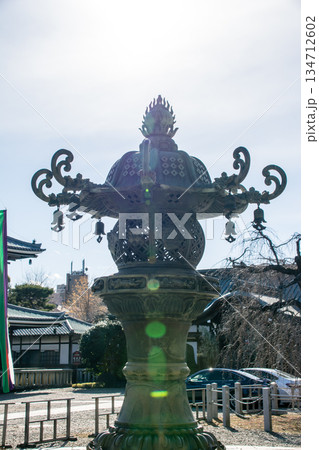 真っ青な快晴と眩しい日差しの下の歴史的な飾りのついた石灯篭　東京の護国寺にて 134712602