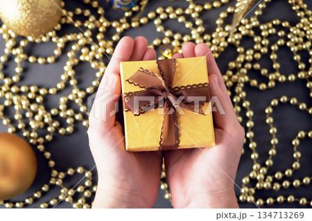 Children's hands are holding a yellow gift box on a Christmas background. Children's hands are holding a yellow gift box on a Christmas background. 134713269