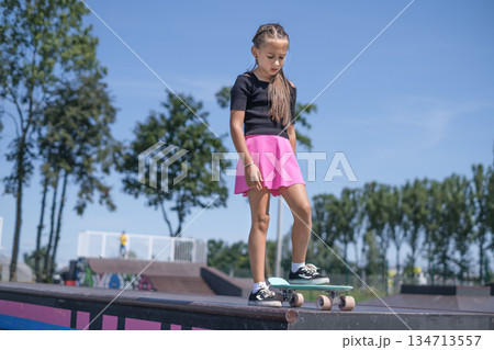 The girl gathers thoughts, concentrates before doing a dangerous skateboard trick on the ramp of the skatepark 134713557