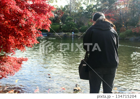 都立公園にて鯉に餌をあげる女性 都立公園にて鯉に餌をあげる女性 134715204