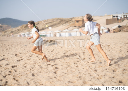 Playful girls running on sandy beach during summer Playful girls running on sandy beach during summer 134716108