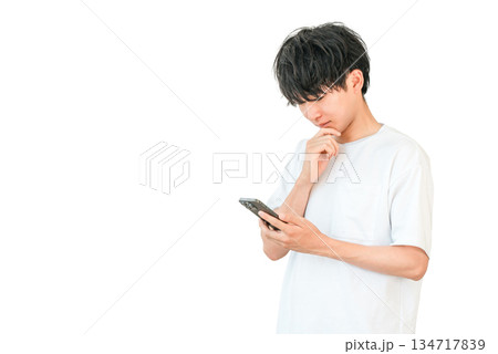 スマホを見ながら考える,検討する,悩む若いアジア人男性 スマホを見ながら考える,検討する,悩む若いアジア人男性 134717839