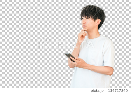 A young Asian man thinking, considering, worrying while looking at his smartphone 134717840