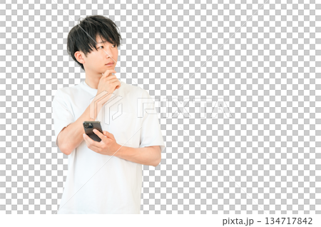 一位年輕的亞洲男子一邊看著智慧型手機，一邊思考、考慮、擔憂 134717842