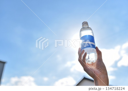 青空とペットボトルを持つ手のイメージ 青空とペットボトルを持つ手のイメージ 134718224