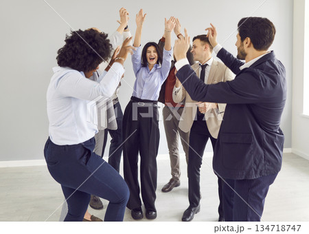 Young funny happy business people and company employees in suits having fun celebrating success 134718747