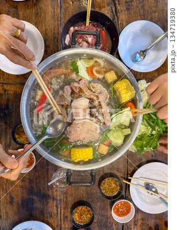 Sliced meat and vegetables cook in a metal grill pot filled with broth and steam, while the center grill browns the meat. Sliced meat and vegetables cook in a metal grill pot filled with broth and steam, while the center grill browns the meat. 134719380