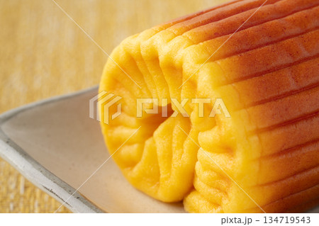 お皿に載せた1本まるごとの伊達巻の端のクローズアップ 134719543