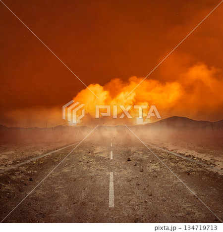 Desolate road stretches towards an apocalyptic scene featuring a massive cloudscape of explosive flames. The landscape is dry and barren. Extreme weather background 134719713
