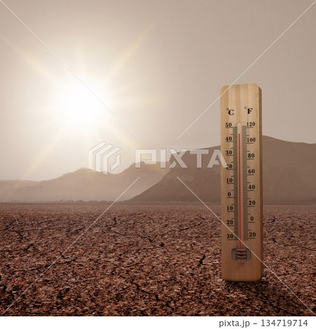 Thermometer registering high temperatures with the sun drenched on an arid landscape background. Extreme weather background 134719714