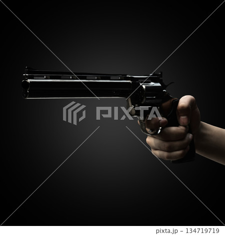 Human hand holding a revolver handgun against a dark background. Concept of gun violence 134719719