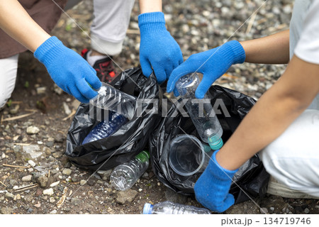 Volunteers wearing aprons and gloves in a cleanup activity. Holding trash bags filled with garbage. Protecting the environment by cleaning up litter 134719746