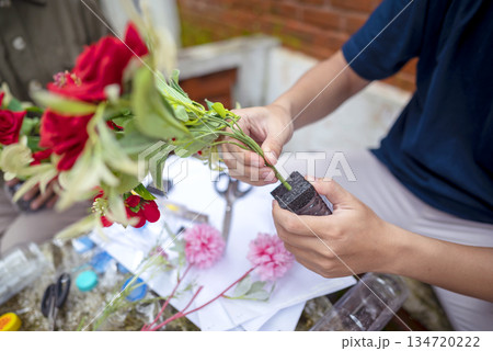 People gathered outdoors, actively participating in a recycling initiative. Decorating with plastic bottles promotes environmental sustainability. Spirit of eco-consciousness 134720222