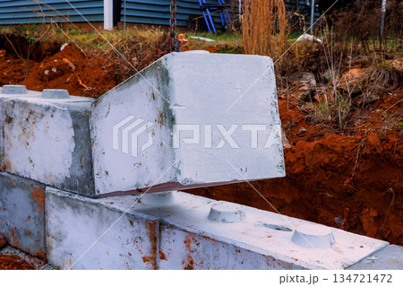Workers place concrete blocks on construction site near building for retaining walls Workers place concrete blocks on construction site near building for retaining walls 134721472